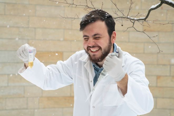 Man in white coat laughing in the snow