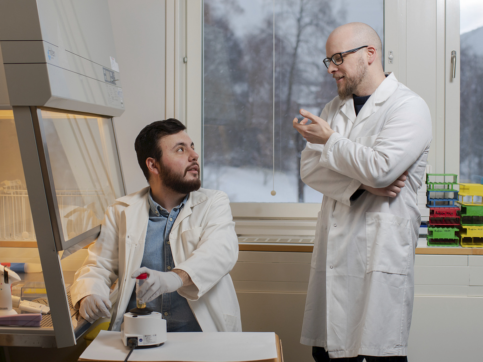 Two men in white coats discussing in lab
