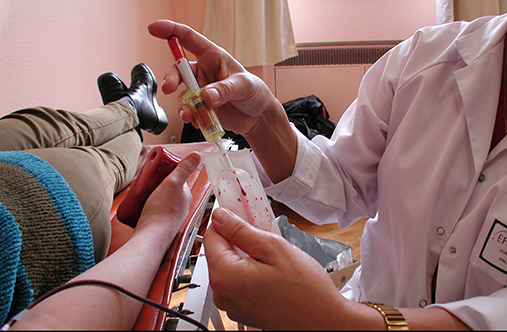 Illustrasjonsbilde av en pleier som tar blodprøve av en liggende pasient.