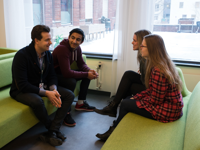 Foto av studiedekanen som sitter i en sofagruppe og prater sammen med tre studenter.