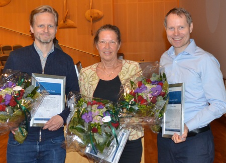 Bilde av de tre forskerne som mottok pris for fremragende forskning, oppstilt smilende med diplomer og blomster i hendene.
