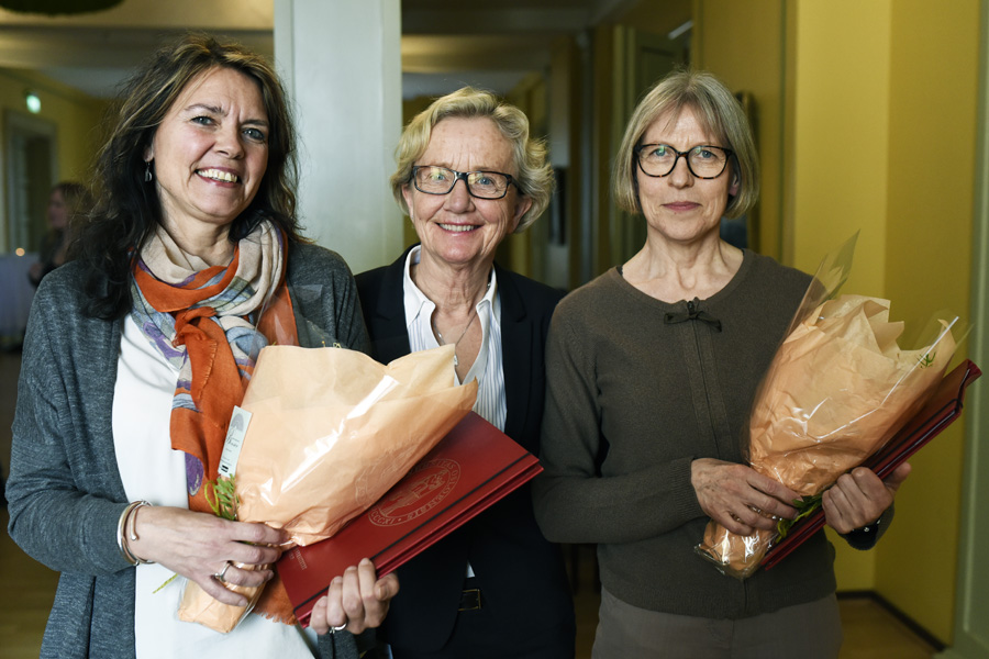 Foto av tre damer som står og smiler, de to ytterste holder hver sin blomsterbukett.