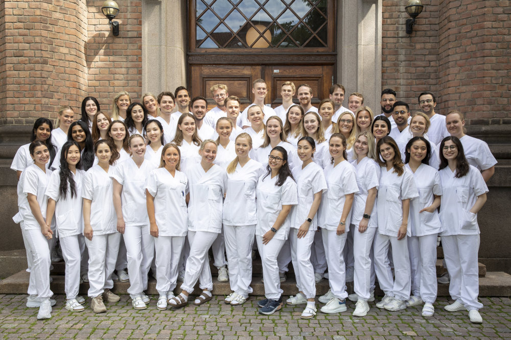 Glade tannlegestudenter i klinikktøy utenfor fakultetet